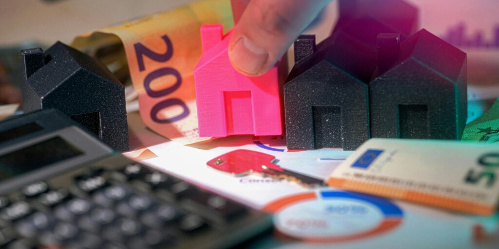 Maquetas de casas con billetes de euro y calculadora — valoración inmobiliaria