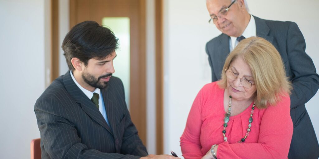 Pareja mayor firmando documentos inmobiliarios con asesor